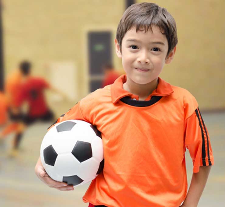 Boy in orange holding soccer ball